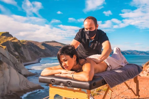A young man performing a massage in nature on the coast near the sea, a dream come true, masseuse