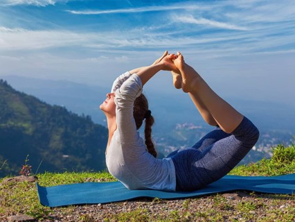 Yoga outdoors, young sporty fit woman doing Ashtanga Vinyasa Yoga asana Dhanurasana, bow pose, in