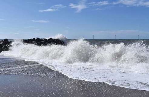 Gentle waves roll evenly to shore under a clear sky