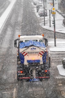 Winter weather, heavy snowfall, city centre traffic, winter service vehicle from