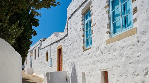 Row of white houses with blue windows under a blue sky, traditional Greek architecture, Chora, Old