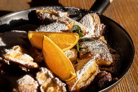 Austrian Kaiserschmarrn, a shredded pancake dessert, served in a skillet garnished with powdered