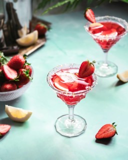 Two elegant glasses of refreshing strawberry cocktail garnished with fresh strawberries and lemon