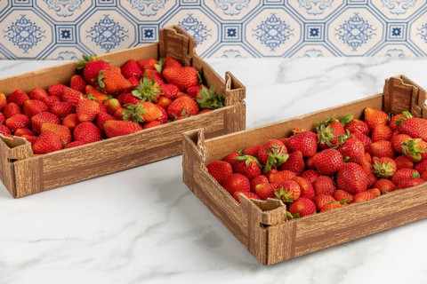 Two boxes of fresh strawberries on a marble slab, blue pattern in the background