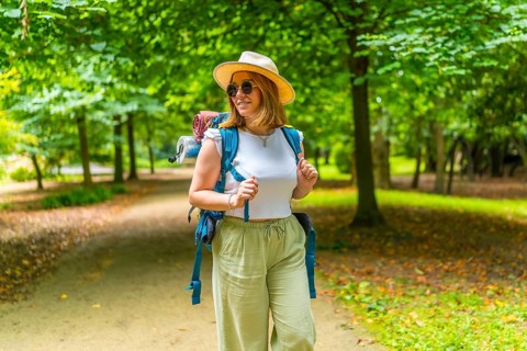 Frontal view of a caucasian adult woman carrying backpack while walking among trees in the forest