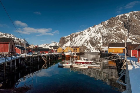 Fishing village with yellow and red houses in front of snow-covered mountains, Nusfjord,