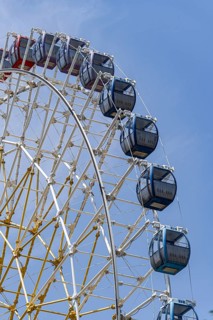 Captivating view of a colorful Ferris wheel towering against a bright blue sky, illustrating a day