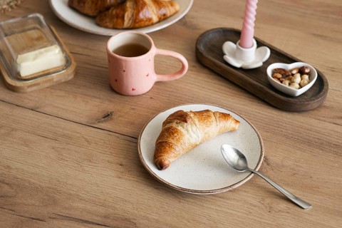 Delicious homemade croissants served on a rustic wooden table with a pink mug filled with coffee,