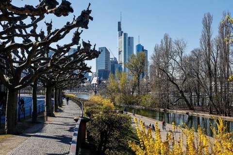 Few people on the banks of the Main in front of the skyline of Frankfurt city centre with banking