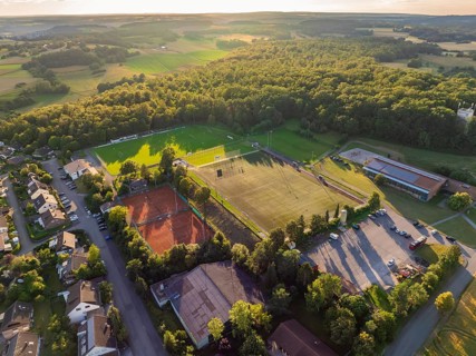 Aerial view of a sports facility with football pitches, tennis courts and surrounding houses and