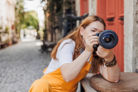 A woman in her 40s captures the charm of Alacati, Turkey with her camera. Dressed in vibrant