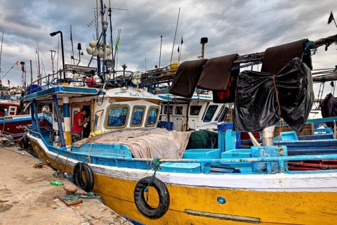 Detailed old fishing boat in the harbor with a variety of equipment under cloudy skies, The