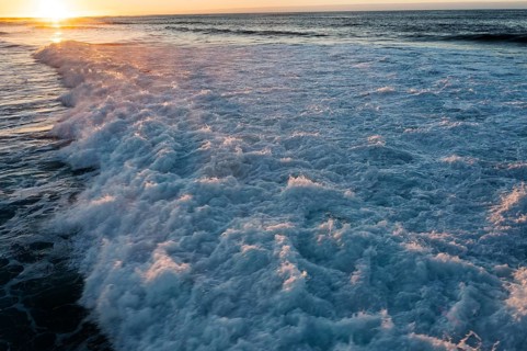 Serene scene with sun gently rising over the crashing waves of Popcorn Beach, Fuerteventura,