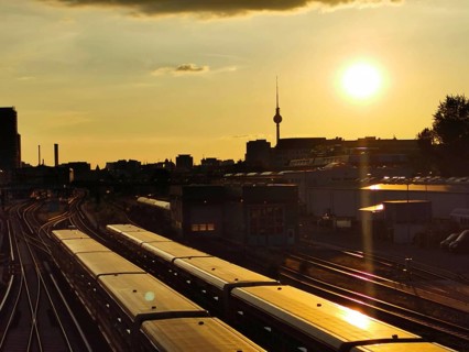 Sunset over train tracks with urban silhouette and Berlin TV tower in the background, Berlin