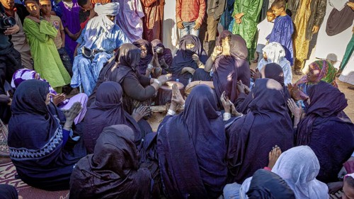 Large group in traditional dress drumming and coming together in a circle, traditional woman