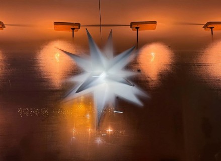 View through a steamed-up window of a café to an illuminated poinsettia, atmospheric lighting and