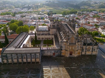 Aerial view of a historic monastery in Gothic architecture, surrounded by buildings and nature in a
