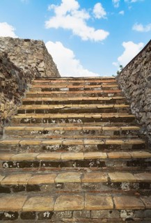 Close-up of old stairs with steps made of terracotta stone tiles and bordered by stone walls at the