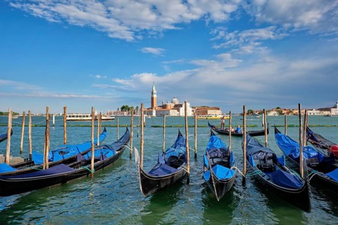 VENICE, ITALY, JUNE 27, 2018: Gondolas and gondolier in lagoon of Venice by Saint Mark (San Marco)