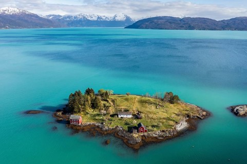 Aerial view of typical red houses on an island in the Hardangerfjord, mountain range in the back,