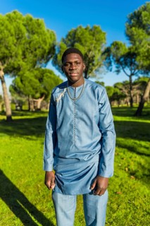 Young african man wearing traditional dashiki attire, posing confidently in a park under the bright