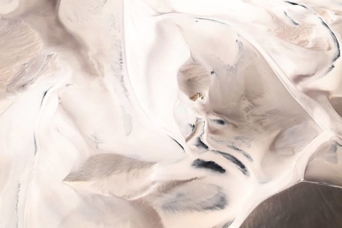 Captivating aerial view showcases swirling, abstract desert patterns whit dunes. Soft shades of