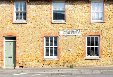 Vintage listed road distance mileplate sign historic old stone building, Fore Street, Castle Cary,
