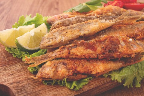 Fried crispy red mullet fish, on a wooden chopping board, with lime, no people