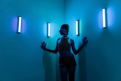 A cyberpunk female model poses against a neon-lit wall, embracing futuristic aesthetics with