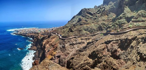 Coast with winding road along the ocean and impressive cliffs, Ponta do Sol in the background,