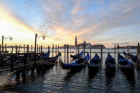 Venetian gondolas near St. Mark's Square in the morning light, in the background the monastery of