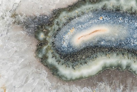 Macro photograph of Brazilian quartz with a central clay tube inclusion, surrounded by vibrant