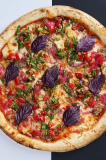 Top view of a freshly baked pizza topped with tomato sauce, mozzarella, lamb, baked eggplant,