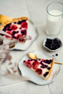 Top view of a slice of berry clafoutis pie filled with blackcurrants and strawberries, presented on