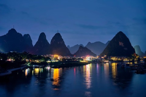 View of Yangshuo town illuminated in the evening with dramatic karst mountain landscape in