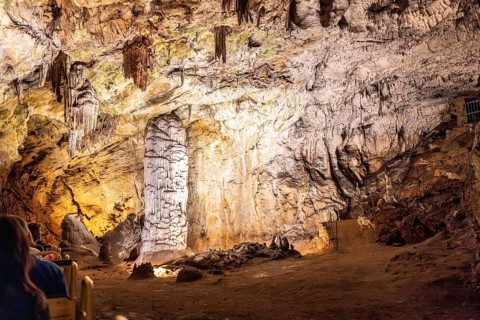 Tourists riding a train inside postojna cave, admiring the stalactites and stalagmites formations