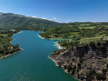 A serene capture of Lago di Fiastra in Italy. Vibrant blue waters are surrounded by lush green