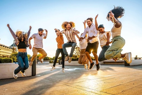 Full length photo of multi-ethnic group of happy friends jumping having fun in the street during
