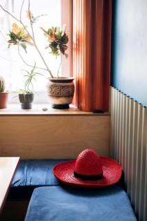 A cozy Mexican interior featuring a vibrant red sombrero on a blue cushioned bench. Sunlight