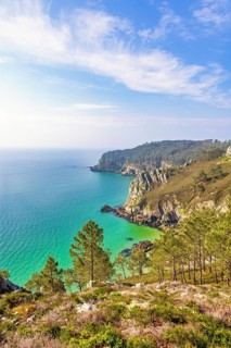 Scenic coastal landscape with steep rocky cliffs covered in green vegetation overlooking a