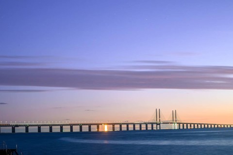 Modern Øresund bridge across the sea at sunset with colorful sky illuminated by a colorful sunset,
