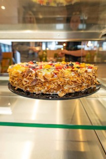 An artistically decorated cake with almond slivers and fruit in a glass display case, Cafe Kuh,