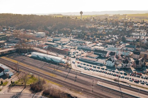 City overview with residential areas, railway tracks and parking spaces in front of a hill,