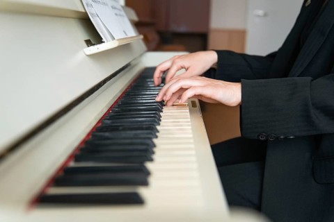 A musician elegantly dressed in a black suit plays the piano, fingers skillfully gliding over the