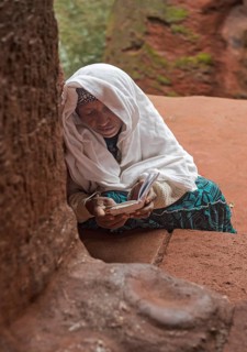 Ethiopian Orthodox believers absorbed in prayer at the entrance to the rock-hewn church of Biete