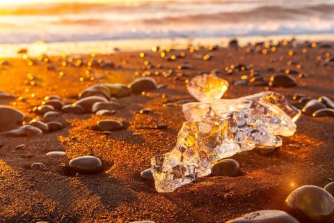 Ice and stones at sunrise with ice on Diamond Beach next to Jokulsarlon in winter in Iceland
