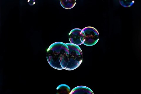 Iridescent soap bubbles in the colours of the rainbow against a black background, Recklinghausen,