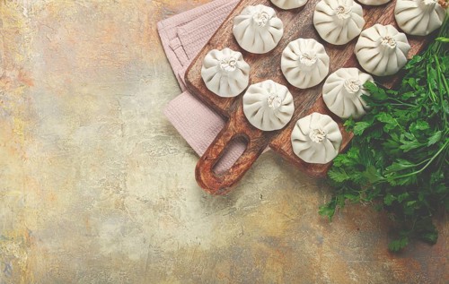 Freshly frozen raw khinkali, on a wooden chopping board, top view, Georgian cuisine, no people
