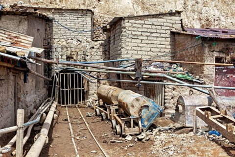 Entrance of a mine with pipes and materials in an older building environment, The Potosi Silver