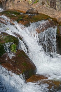 A detailed waterfall flows over moss-covered rocks in a stony landscape, Cascada del Diablo,
